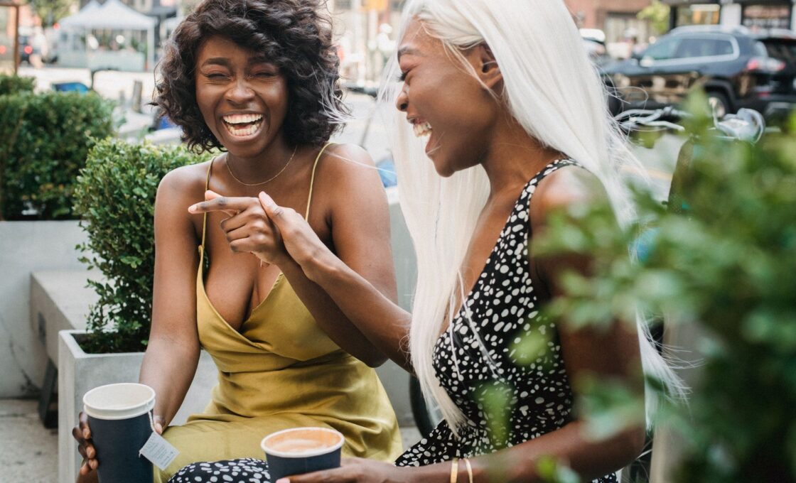 Two women friends talking and laughing together at a cafe