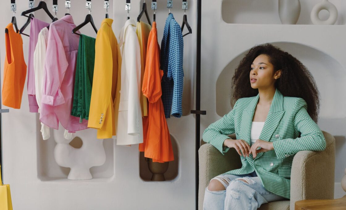 Woman in a tailored blazer checking clothing tags on a rack while fall shopping