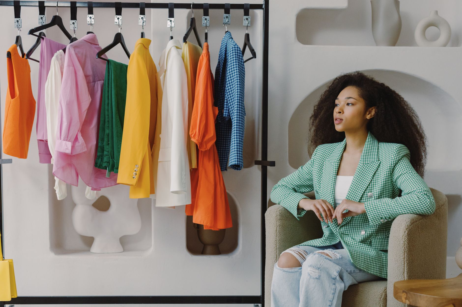 Woman in a tailored blazer checking clothing tags on a rack while fall shopping