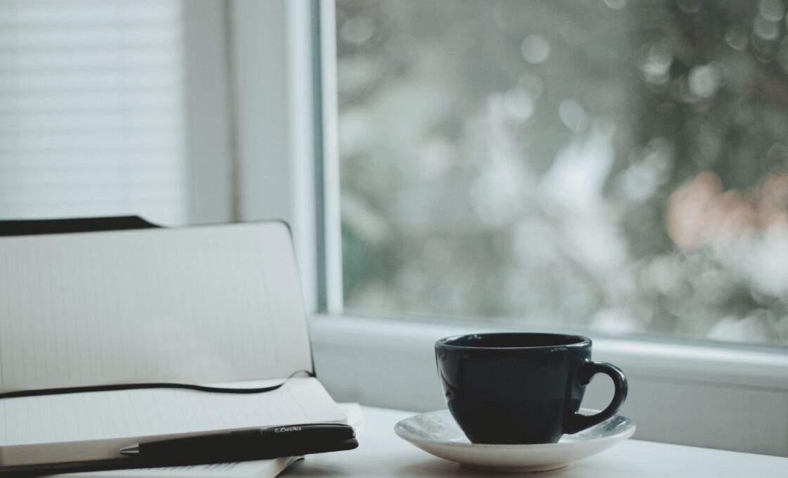 Woman journaling with coffee by a window in the morning