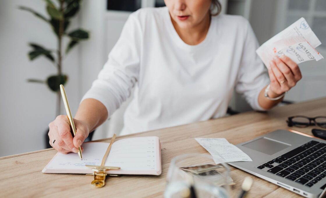 Woman reviewing a calendar and notebook while planning monthly savings