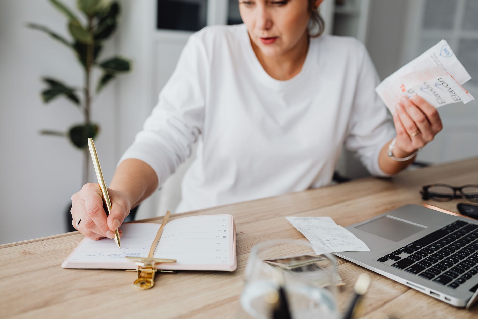 Woman reviewing a calendar and notebook while planning monthly savings
