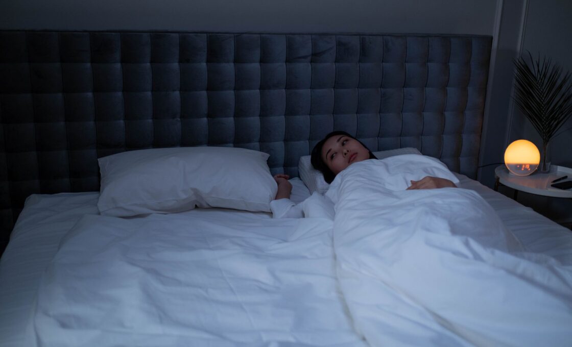 Woman lying awake in bed in the early morning hours