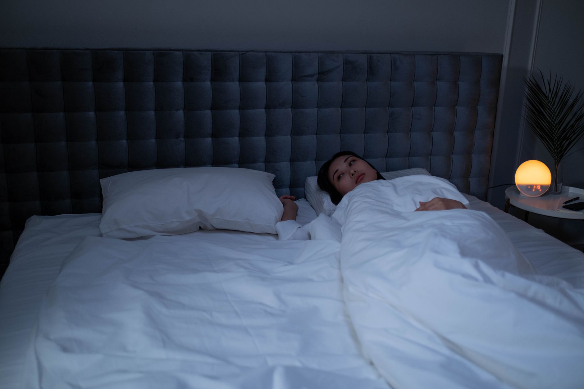 Woman lying awake in bed in the early morning hours