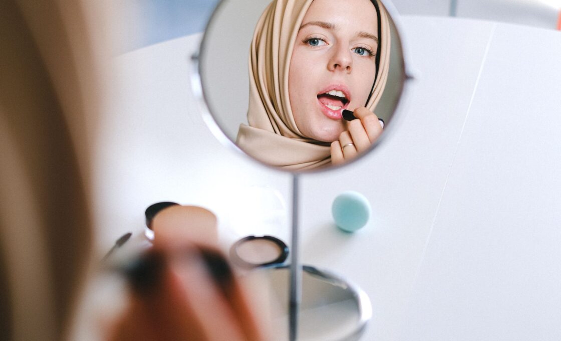Woman applying foundation makeup in warm summer light