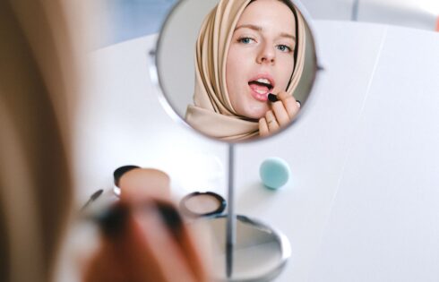 Woman applying foundation makeup in warm summer light