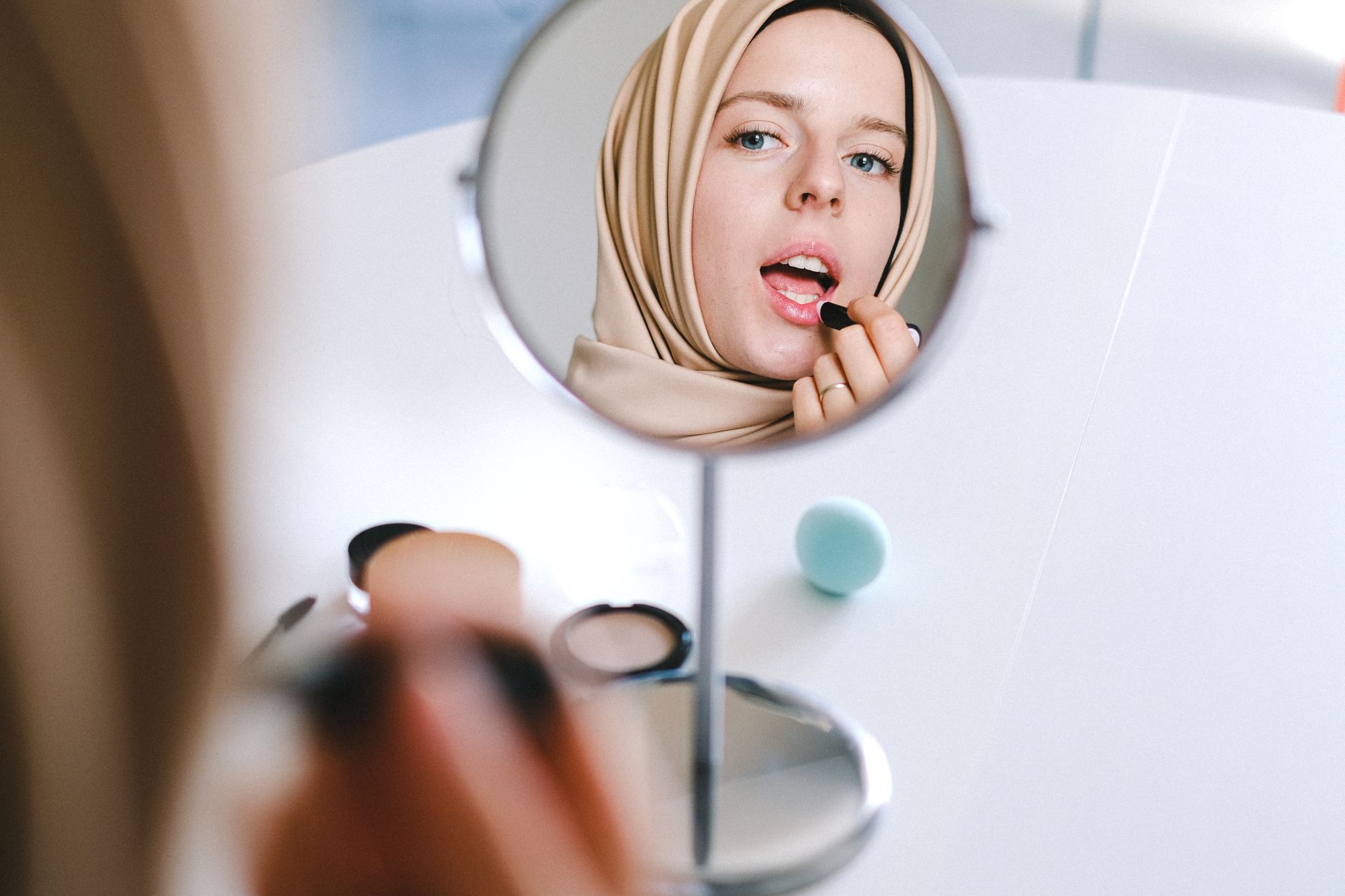 Woman applying foundation makeup in warm summer light