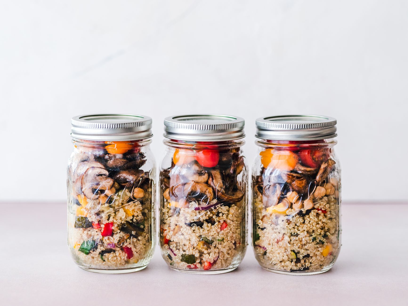 Glass containers of prepped grains, vegetables, and greens on a kitchen counter
