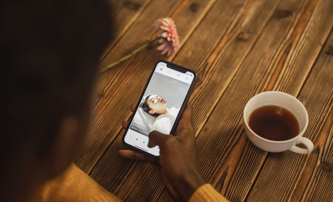 Woman looking at a dating app on her phone while sitting in a cafe