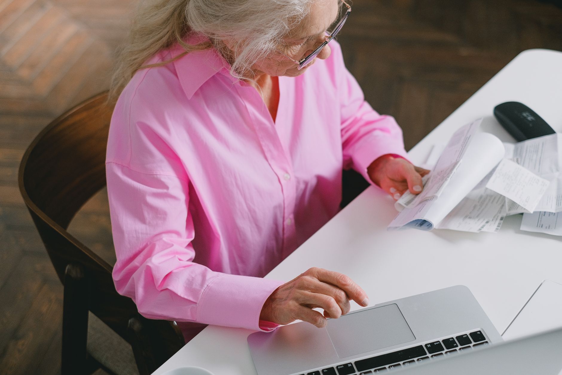 Woman at a kitchen table reviewing health savings account statements on a laptop