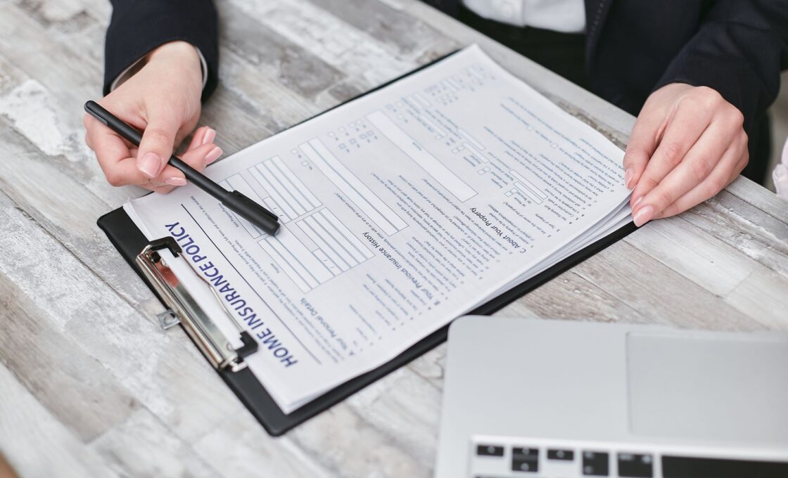 Hands reviewing a health insurance policy document during ACA open enrollment