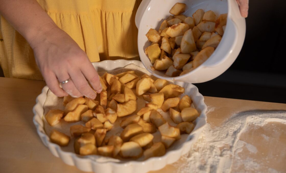 Woman preparing a homemade apple pie with fresh fall baking apples