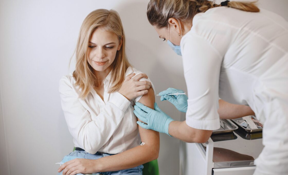 Nurse giving a woman a flu shot in her upper arm at a clinic