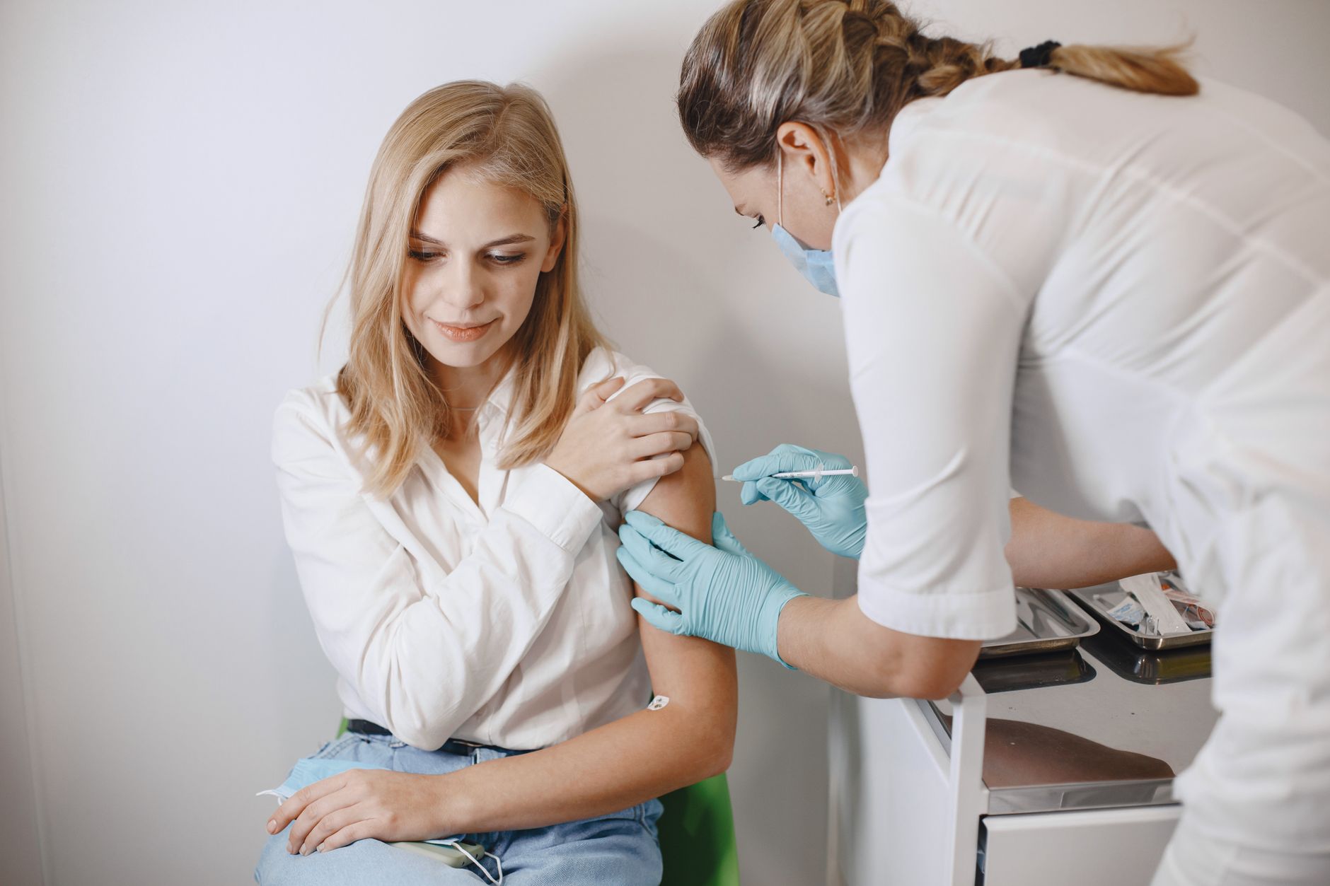 Nurse giving a woman a flu shot in her upper arm at a clinic