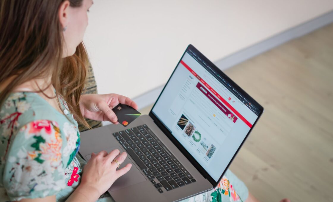 Woman holding a credit card while shopping online on a laptop, planning holiday buy now pay later payments