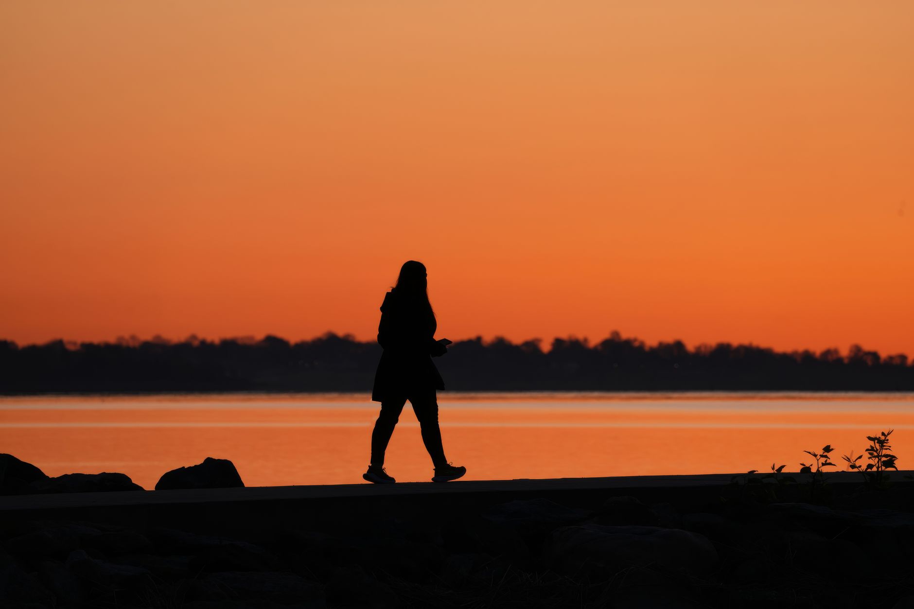 Silhouette of a woman walking at sunset as evenings get darker after daylight saving time ends