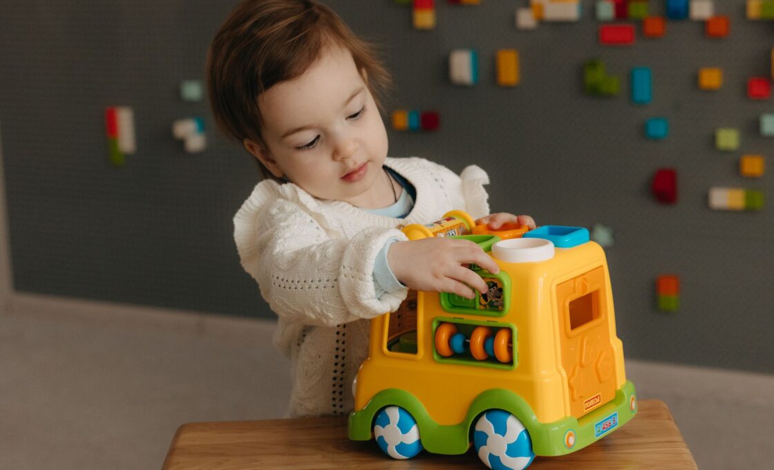 Young child playing with a toy truck indoors, the kind of daycare-age care a dependent care FSA or child care tax credit helps pay for