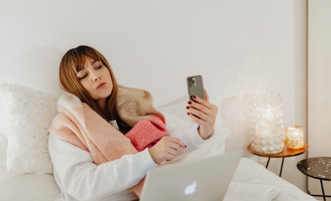 Woman staying warm under a cozy blanket in bed on a cold winter night