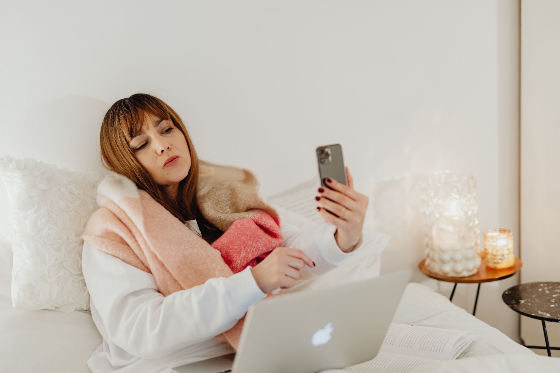 Woman staying warm under a cozy blanket in bed on a cold winter night