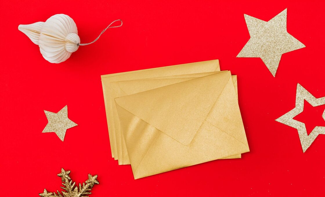 Gold holiday envelopes on a red background, ready for holiday tips