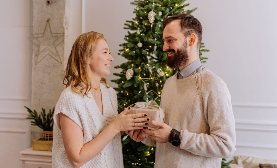 Couple exchanging wrapped Christmas gifts at home while deciding how much to spend on each other