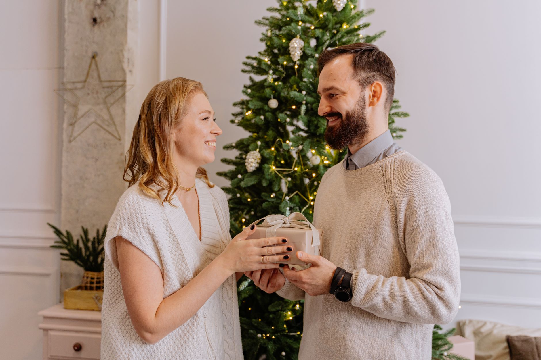 Couple exchanging wrapped Christmas gifts at home while deciding how much to spend on each other